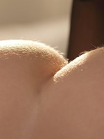 Dakota Rae removes her top in a dim, sunlit room